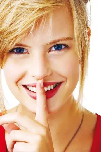 Smiling woman with finger on lips